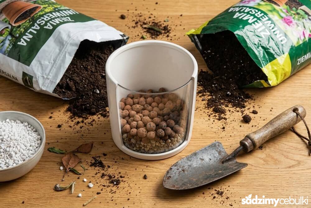 Przygotowanie doniczki dla kalii: drenaż na dnie oraz ziemia i perlit obok narzędzi ogrodniczych.